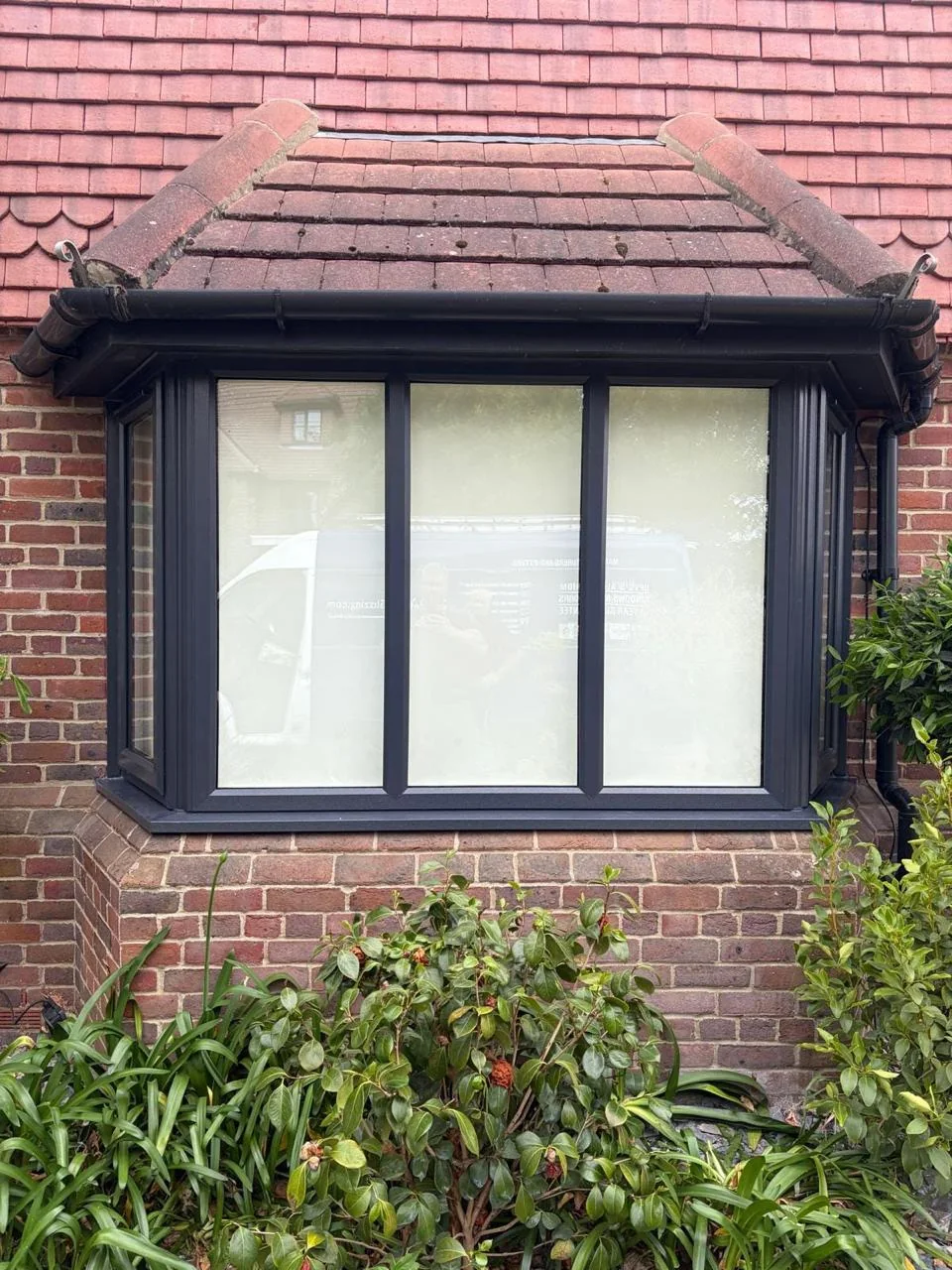 Dark grey bay window fitted to a brick home