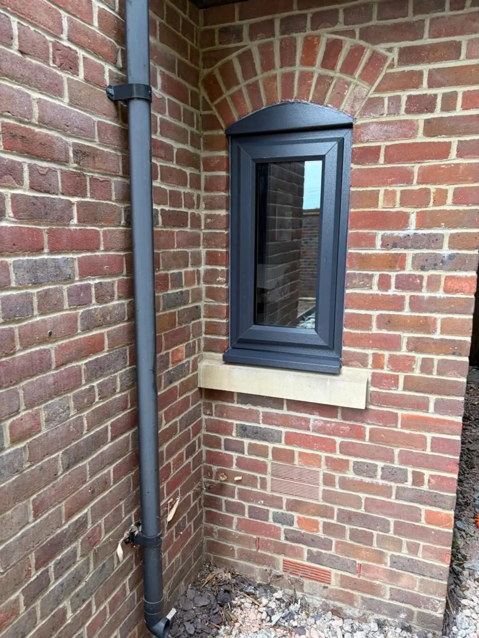 Dark grey casement window fitted into a brick wall