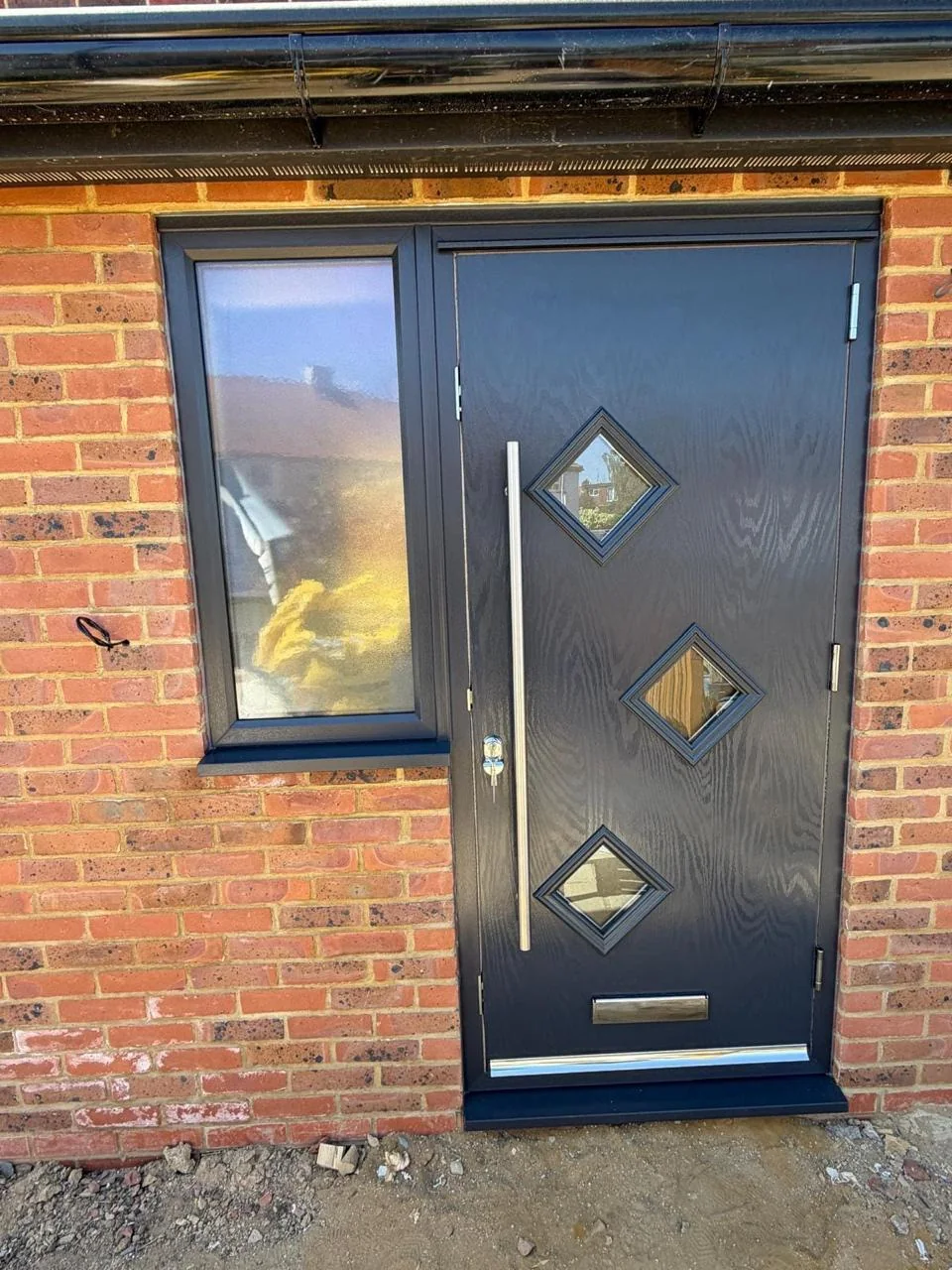 Dark composite entrance door with diamond glazing and a side light