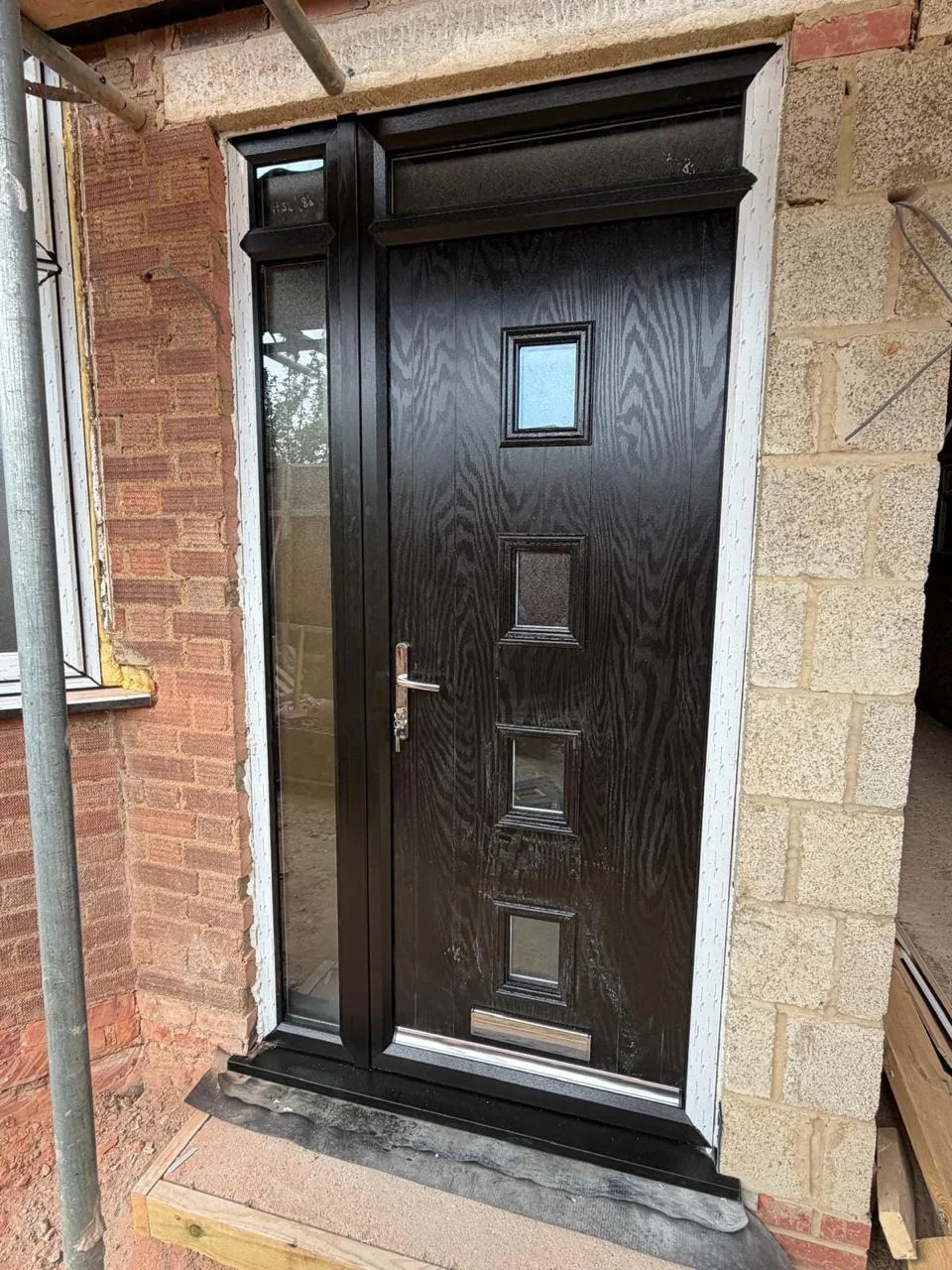 Black composite entrance door with narrow glazing and a side light
