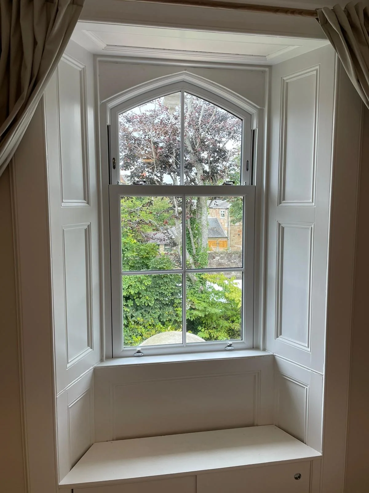Pointed arch sash window viewed from a panelled interior