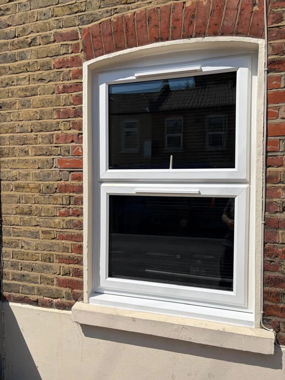 White sash window fitted in a traditional brick exterior