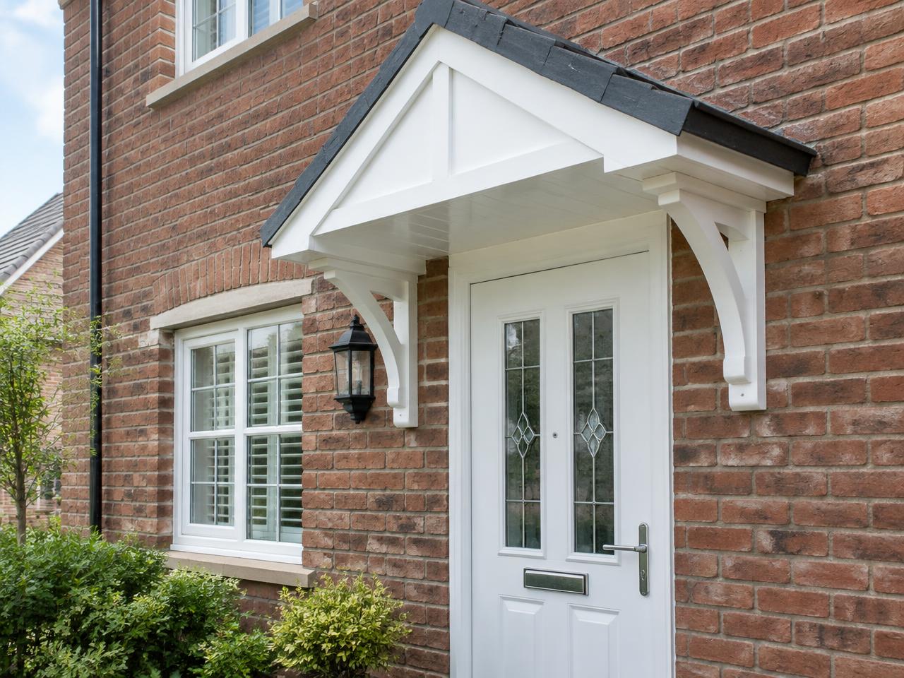 Classic white pitched door canopy with decorative brackets over a front door