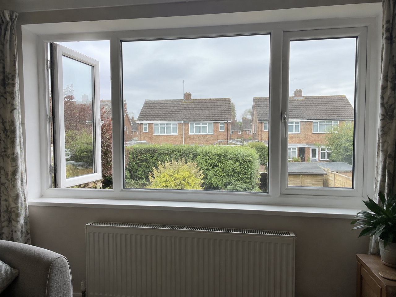 White side-hung casement window opening outwards in a living room