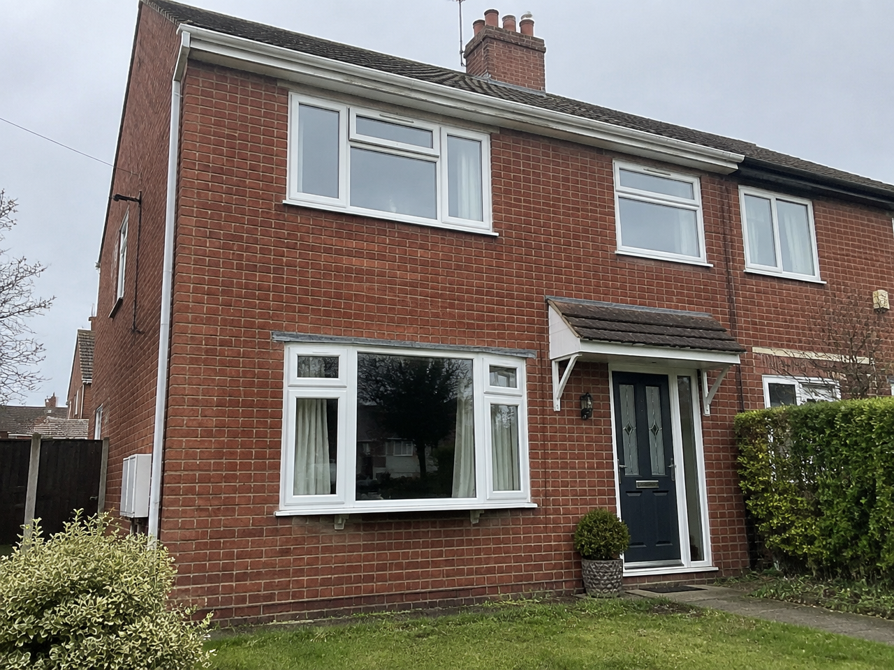 White casement windows on a typical red-brick semi-detached home