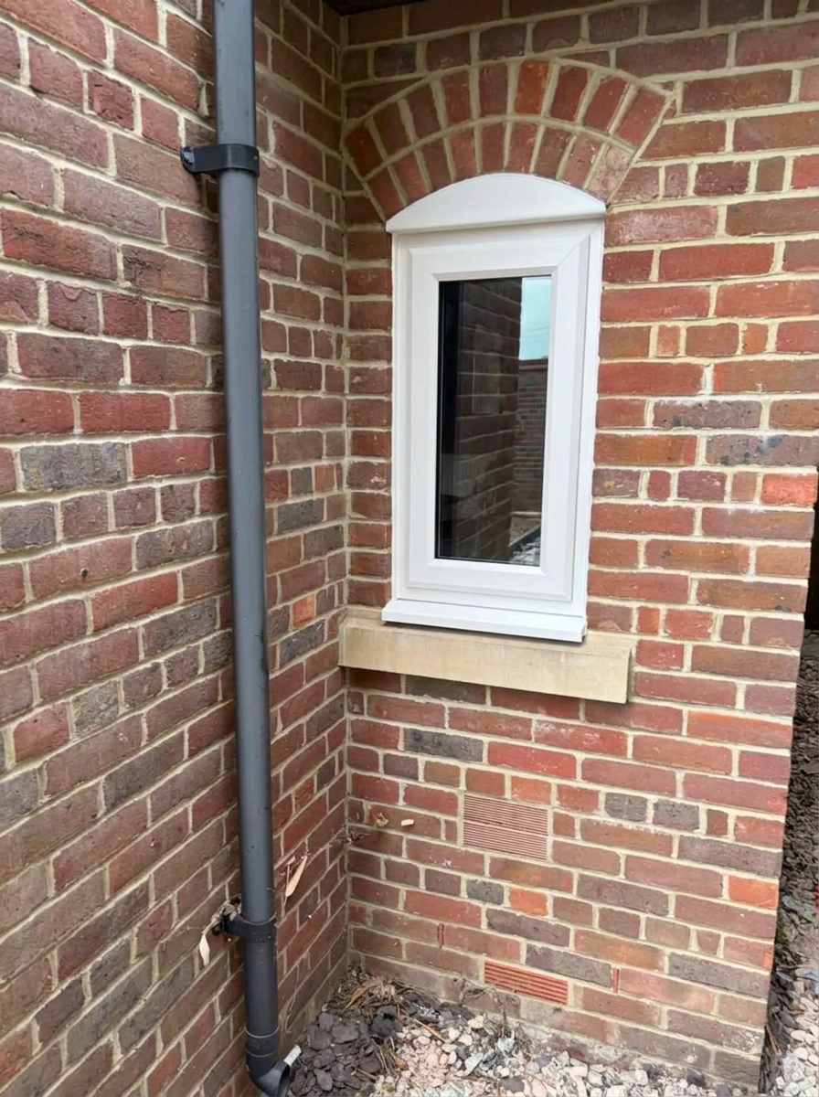 White uPVC casement window fitted into a brick wall
