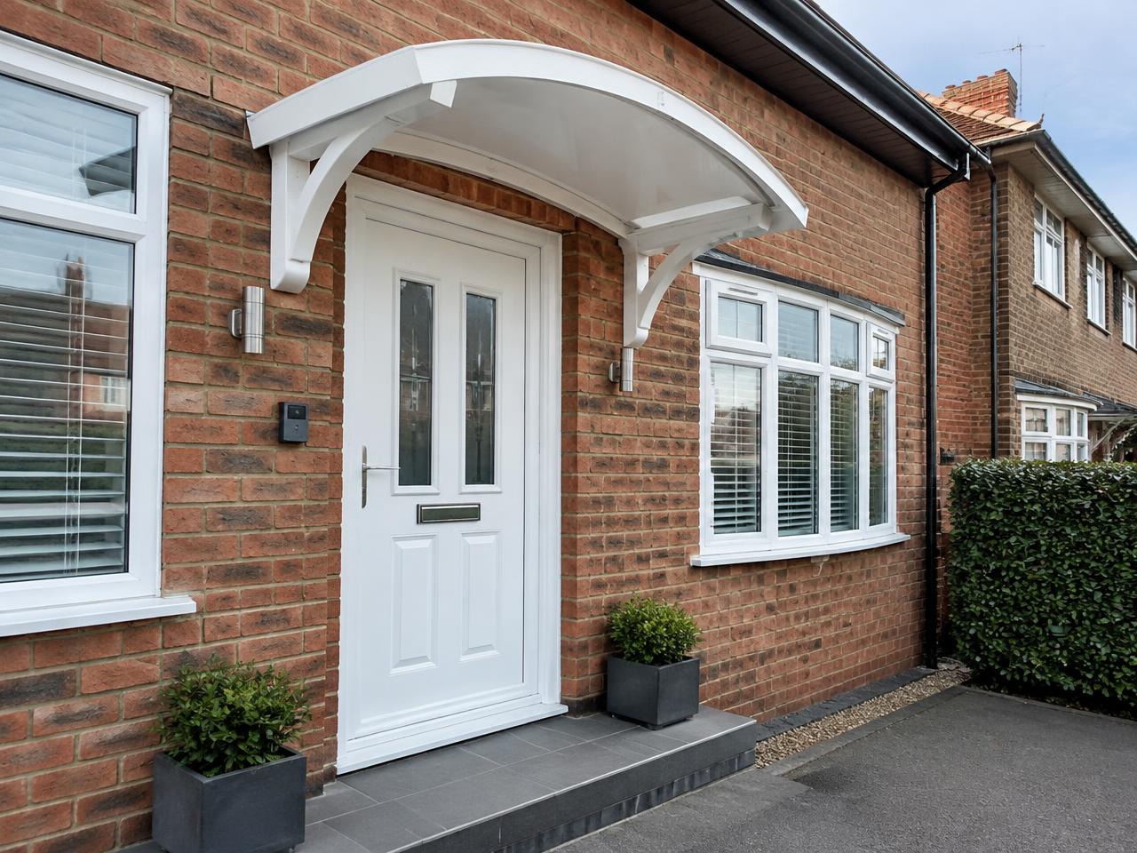 Curved white uPVC door canopy above the front door of a brick house