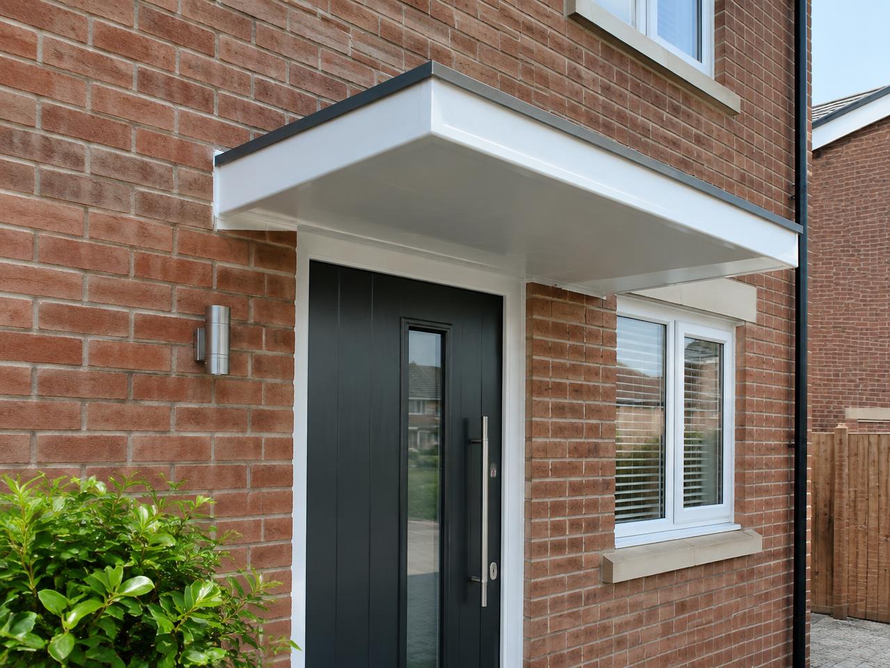 Simple flat white door canopy above the front entrance of a modern brick home